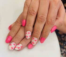 Stylish pink floral nail art on hands with heart-shaped design showcasing creative manicure and...