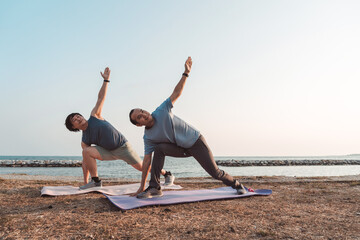 Men doing exercise together and sporty active outside sea beach