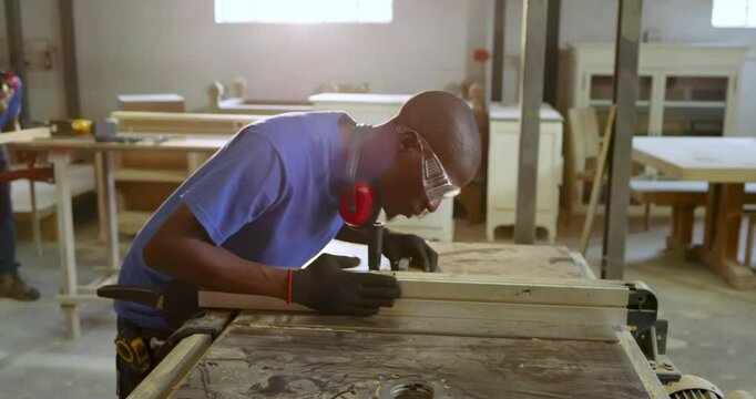 African American man positioning plank at shop table saw cutting with push block for fine boards