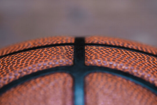 Symmetrical, detailed close-up macro shot of a textured leather dark orange basketball showing the individual dimples on the ball and the black rubber stripes. Sport and Game concept.