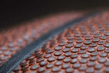 Extreme Close-up detail macro shot of a textured leather dark orange basketball showing the individual dimples on the ball and the black rubber stripes on a black background. Sports Equipment.