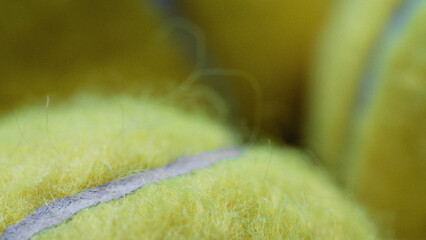 Detailed macro shot of three tennis balls in dramatic lighting in Fluorescent, Optic yellow or Electric lime colour, showing fuzzy covering. Sports Equipment. Ball Sport and Game concept.