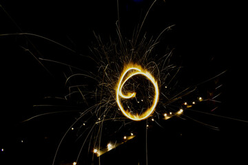Long exposure shot of a sparkler creating a glowing circle in the dark.