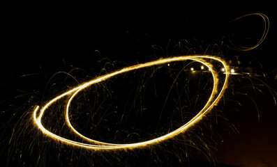 Long exposure shot of a sparkler creating a glowing circle in the dark.
