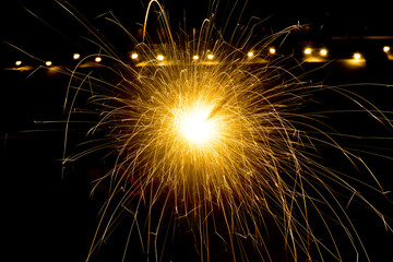 Bright burst of golden sparks from a firework against a dark background, celebrating.