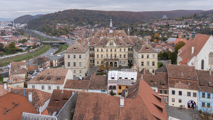 Obraz premium Aerial, drone view of Sighișoara City Hall, Primăria Sighișoara, in the Transylvania region of Romania. Târnava Mare River visible. Beautiful famous must-see tourist attraction. Travel destination, ea