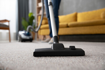Person vacuuming carpet in living room close up