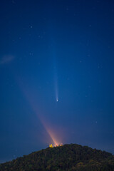 A stunning night sky features Comet C/2023 A3 (Tsuchinshan–ATLAS) streaking above Wat Phra That Doi Suthep, Chiang Mai, Thailand, with its glowing temple lights on the mountain peak.