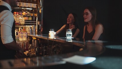 Portrait of VIP guest in beautiful woman making a toast in cheers at luxurious nightclub at vibrant nightlife party. Sitting at counter bar talking with barman atmosphere party lifestyle. Vinosity.