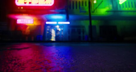 Neon signs cast colorful reflections on the wet pavement, creating a vivid atmosphere. The surroundings feature closed shops in a quiet urban setting at night. - Powered by Adobe