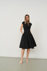 Fototapeta premium Elegant female model standing in a stylish black dress in a studio setting