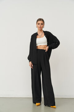 Stylish female model posing in fashionable indoor studio setting with elegant attire
