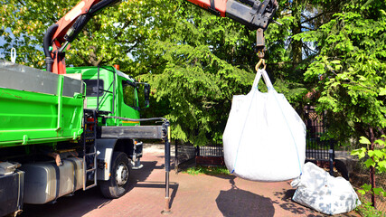 Crane with a big bag of stones. It is a white big bag with decorative stones for the property.