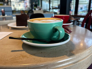 Cafe. Green cup of cappuccino on the table.
