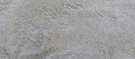 Close-Up Texture of Natural Beach Sand.High-resolution close-up image of natural beach sand texture. Fine grains with a mix of light beige and grey tones, ideal for use as background, texture overlays