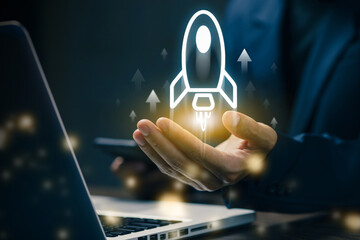 Businessman launching a virtual rocket icon above laptop, symbolizing startup growth, innovation, business development, and successful project launch in the digital age.