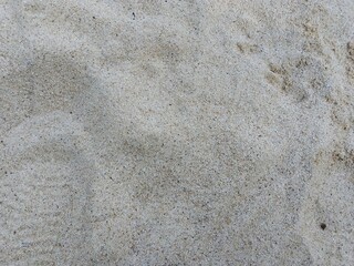Close-Up Texture of Natural Beach Sand.High-resolution close-up image of natural beach sand texture. Fine grains with a mix of light beige and grey tones, ideal for use as background, texture overlays