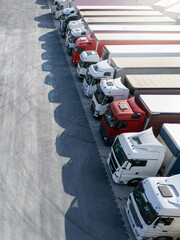 Aerial view of a large truck parking lot at a logistics hub, with multiple commercial semi trucks...