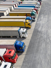 Aerial view of a large truck parking lot at a logistics hub, with multiple commercial semi trucks...