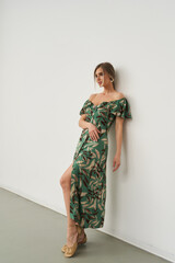 Stylish female model poses gracefully indoors in a beautiful floral dress