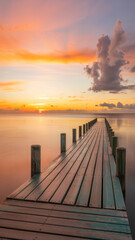 Long wooden pier extending into still ocean under dramatic sunrise sky with vibrant cloud reflections

