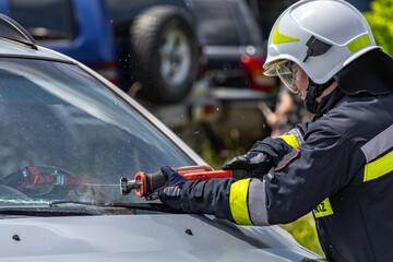 A firefighter from the rescue team cuts out a car windshield,