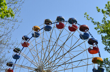 Ferris wheel on a blue sky in city park. Amusement park ride. Summer holiday carousel entertainment.