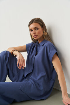 Stylish woman posing in modern indoor studio in chic blue outfit