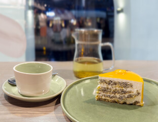 A piece of cake and tea on a wooden table in a cafe, close-up. 
