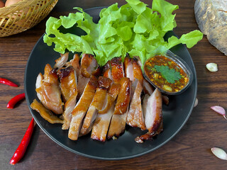 Thai Grilled Chicken with Spicy Dipping Sauce and Fresh Lettuce on Black Plate – Traditional Thai...