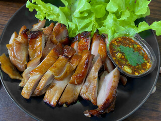 Thai Grilled Chicken with Spicy Dipping Sauce and Fresh Lettuce on Black Plate &ndash; Traditional Thai Cuisine