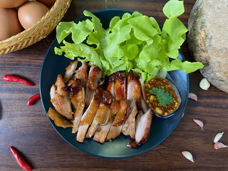 Thai Grilled Chicken with Spicy Dipping Sauce and Fresh Lettuce on Black Plate &ndash; Traditional Thai Cuisine