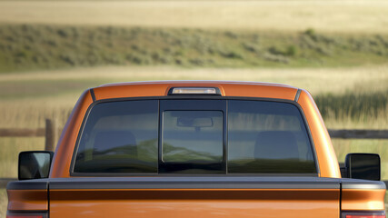Close-up of the rear window and tailgate area of an orange light brown pickup truck. The background is a blurred countryside scene. Photo mockup for decals.