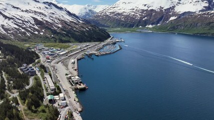 Whittier, USA, flying across the head of "Passage Canal" away from City of Whittier - located on Kenai Peninsula - with port, harbor and mountains around the city  - 4k aerial video footage