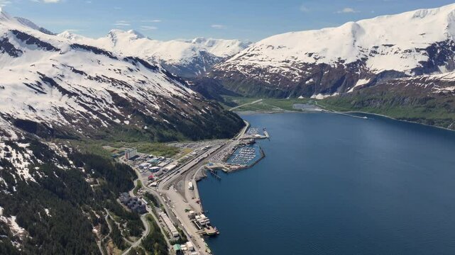 360&deg; right turn, 4k aerial video footage of mountain landscape around Whittier, Alaska, with Cityscape, Harbour, Ferry Terminal and snow covered mountain peak surrounding the "Passage Canal" 