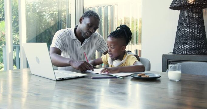 African American father guiding school-age son writing in notebook and teaching counting at home