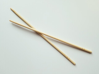 Wooden chopsticks resting on a plain surface hinting at Asian cuisine and dining culture