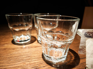 Three empty glasses on the wooden table in the dark