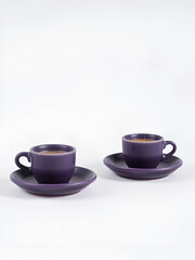 Obraz premium Tiny espresso cups in matte purple stoneware, paired with matching saucers for a minimalist coffee setup.
