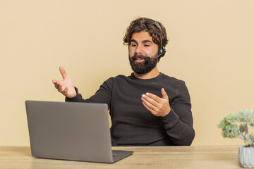 Young Indian businessman wearing headset, call center or support service operator helpline, talking...