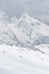 Skiers descending a snowy slope on Mount Elbrus, Kabardino-Balkaria, Russia, with majestic snow-covered peaks in the background