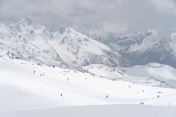 Obraz premium Skiers descending a snowy slope on Mount Elbrus, Kabardino-Balkaria, Russia, with majestic snow-covered peaks in the background