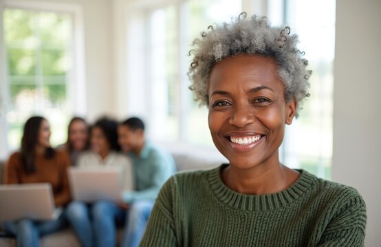 Smiling senior African American woman with multiracial friends in background. Elderly lady enjoys life, happy together with friends, family at home. Portrait of cheerful, attractive, beautiful woman