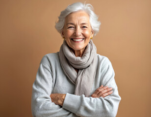 Joyful elderly woman smiles with arms crossed against studio background. Happy senior female smiles showing teeth. Oral health and dental care. Confident old lady. Positive attitude to aging concept.