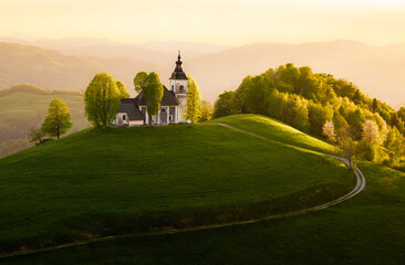 Sunset over a serene hilltop church in Slovenia with lush greenery
