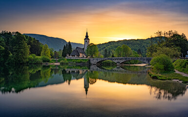 Misty evening at Bohinj with serene lake and church reflected in the water