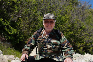 Aged smiling man in camouflage clothing and sunglasses outdoors