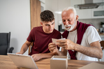 Grandfather and grandson unboxing a gift and reading greeting card