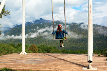 Dream and travel concept, Young beautiful woman happy on swing flying in the sky over stunning mountain view
