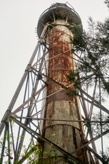 Old rusty lighthouse against the grey sky